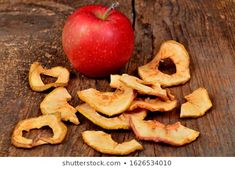 an apple and some cut up pieces on a wooden table with the peels still attached