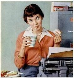 a woman is drinking from a cup while sitting at a desk with a typewriter