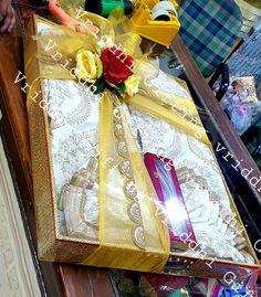 a gift wrapped in yellow ribbon and tied with a rose sits on top of a table