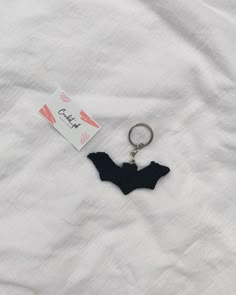 a keychain with a black bat hanging from it's side on a white sheet