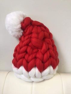 a red and white knitted hat on top of a white surface