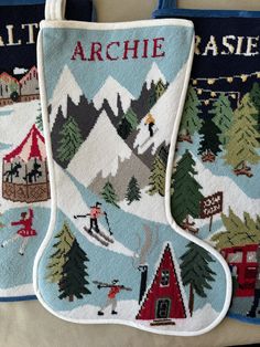 two christmas stockings hanging from the side of a bag with skis and houses on them