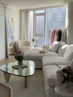 a living room filled with furniture and a glass top table in front of a window