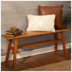 a wooden bench with a pillow on top of it and a book next to it