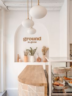 a kitchen with white walls and wooden counter tops, hanging lights above the counter area