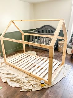 a wooden bed frame sitting on top of a hard wood floor next to a baby crib