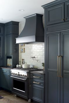 a kitchen with black cabinets and stainless steel stove top oven, built - in range hood