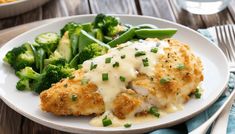 a white plate topped with chicken covered in gravy next to broccoli