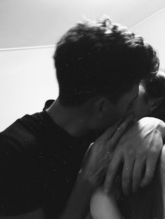 a man and woman kissing each other in black and white