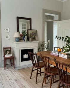 a dining room table and chairs in front of a fireplace with pictures on the mantle