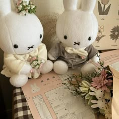 two stuffed animals sitting next to each other on top of a table covered in flowers