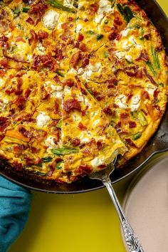 a pizza sitting on top of a pan covered in cheese and toppings next to a spoon