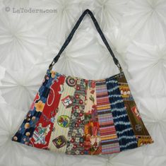 a multicolored purse sitting on top of a white table next to a wall