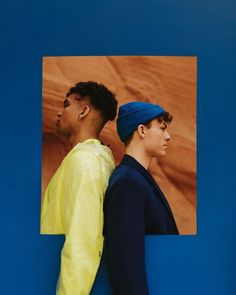 two young men standing next to each other in front of a blue and orange background