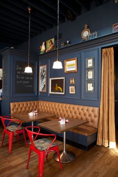 a restaurant with blue walls and leather booths, red chairs and pictures on the wall