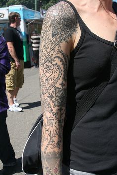 a woman with a tattoo on her arm is standing in front of some people at an outdoor event