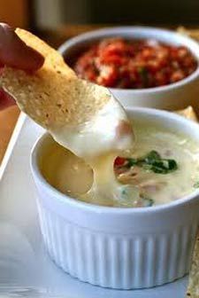 a person dipping tortilla chips into a bowl of dip