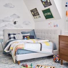 a child's bedroom with blue and white bedding, clouds painted on the wall