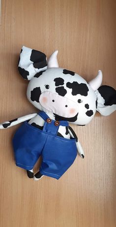 a stuffed toy cow wearing blue shorts on a wooden floor