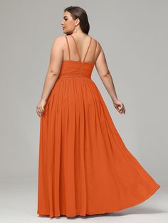 a woman in an orange dress is looking back at the camera and has her hand on her hip