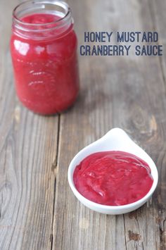 a small white bowl filled with cranberry sauce next to a jar of honey mustard