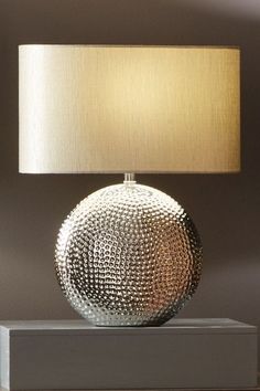 a lamp that is sitting on top of a table next to a mirror ball with a beige shade