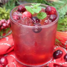 a drink with cherries and mint garnish in a glass on a table