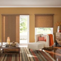 a living room filled with furniture and windows covered in shades of brown, orange and white