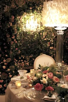 the table is set for dinner with flowers on it and candles in front of them