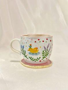 a yellow duck sitting on top of a white cup