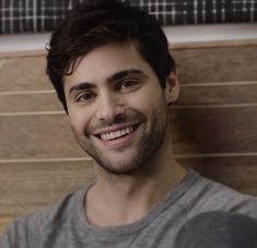 a man smiling and wearing a gray shirt