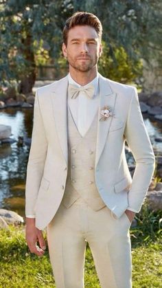 a man in a white tuxedo and bow tie standing next to a river