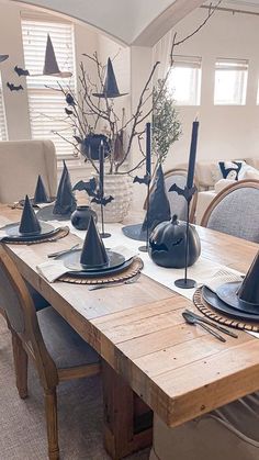 a dining room table set for halloween with black witches hats on the centerpieces