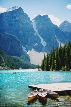 two canoes are docked at the edge of a mountain lake