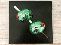 two green and red lollipops sitting on top of a wooden table next to each other