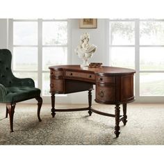 an antique desk and chair in front of large windows