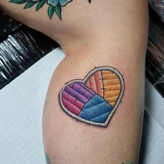 a colorful heart tattoo on the left thigh