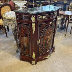 an ornately decorated table with marble top in a room filled with chairs and tables