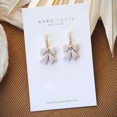 Our trendy bow dangles are oh so adorable and perfect for any time of year. These are handcrafted from clay and feature dainty pearl accent posts that will complement any outfit. COLOR: SPECKLED OATMEAL. Size: Approximately 1 inch from top of posts to bottom. THE DETAILS -Earrings are finished with gold plated faux pearl posts and include rubber backings -Shipped via USPS with tracking *Every pair is uniquely made and slight variations may occur during the creative process. Earrings Handmade Clay, Dangle Pearl Earrings, Pearl Earrings Handmade, Trendy Bows, Pearl Bow, Pop Up Event, Bow Earrings, Pearl Earrings Dangle, Gold Sparkle