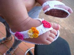 a baby's feet wearing crocheted sandals with flowers