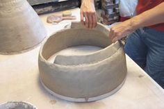 a woman is making a vase out of cement