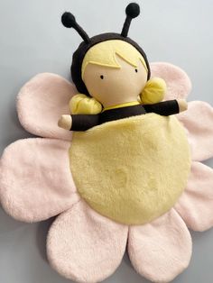 a stuffed toy is laying on top of a flower shaped object that looks like a bee