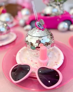 a pink table topped with sunglasses and a teapot filled with confetti on top of a plate