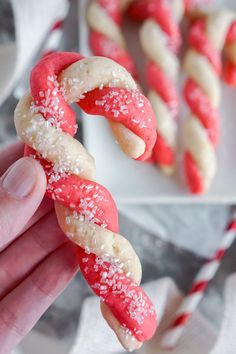 a hand holding up a pretzel with red and white sprinkles