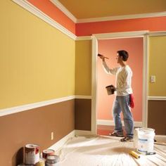 a man is painting the walls in an empty room with yellow and orange paint on it