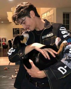 a young man holding a small dog in his arms and kissing it's face