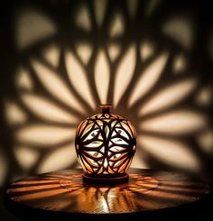 a vase sitting on top of a wooden table under a shadow cast by a lamp