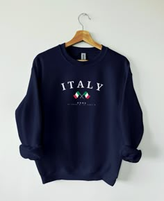 PRODUCT DETAILS & SIZING Italy, a land of art, history, and exquisite cuisine, enchants with its timeless beauty and cultural richness, making it a destination that leaves a lasting impression on all who visit. Our Italy sweater is available in multiple different colors. Made from high-quality materials, this sweater features a classic design with a modern twist. Italy sweater fits both men and women perfectly, and you can go a size up if you want a looser fit. This sweatshirt is a unisex heavy blend crewneck sweatshirt with pure comfort. These garments are made from polyester and cotton.  - 50% cotton, 50% polyester   - Medium-heavy fabric (8.0 oz/yd² (271.25 g/m - Loose fit   - Sewn-in label   - Runs true to size   SHIPPING AND PRODUCTION TIME   - 2-7 working days.   CARE INSTRUCTIONS Italy Shirt, Football Sweater, Italian Gifts, Sweater Fits, Italy Outfits, Embroidered Hoodie, Hoodie Design, Really Cute Outfits, Sew-in Labels