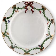 a white plate with christmas decorations and bows on the rim, decorated with holly leaves