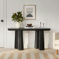 a black table with two white vases on it and a plant next to it